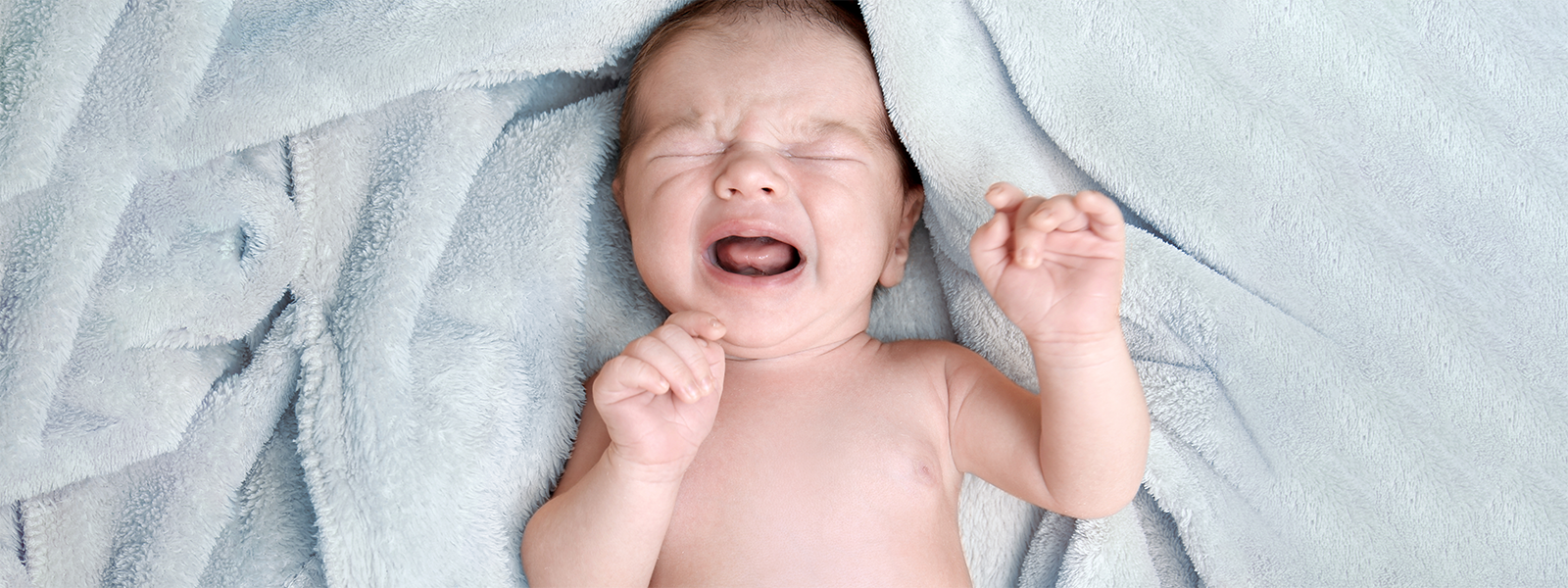 Crying baby on the ground facing up.