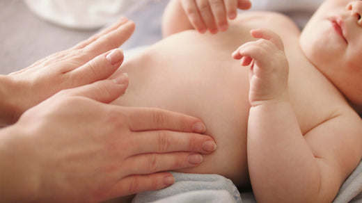 Bébé couché avec la maman caressant son ventre.