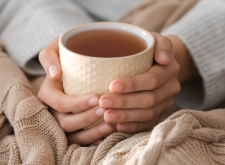 Mains tenant une tasse de thé.