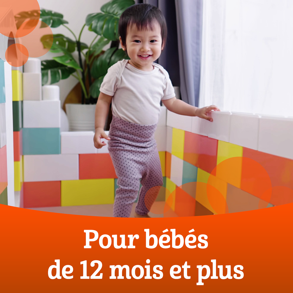 Bébé souriant debout, se tenant à une rampe.