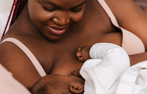 Femme allaitant et souriant à son bébé.
