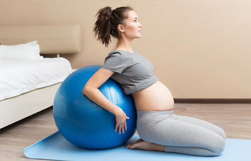 Femme enceinte faisant de l’exercice sur un ballon.