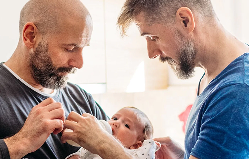 Deux hommes donnant le biberon à un bébé.